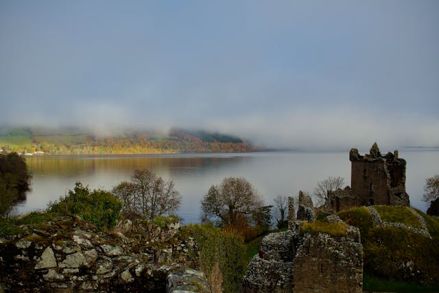 Castillo en ruinas a orillas de un lago bajo la niebla