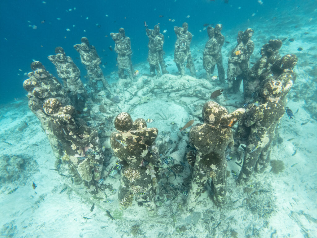 Statues immergées formant un cercle sur un fond sableux